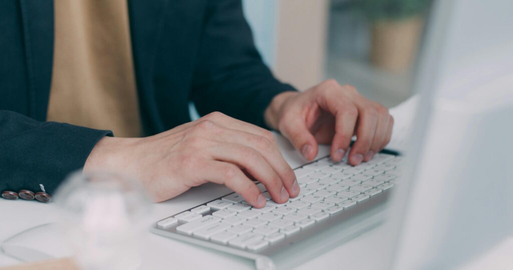 pexels-photo-30535622-30535622 Close-up of hands typing on a white keyboard in an office setting. Ideal for business or technology themes.
