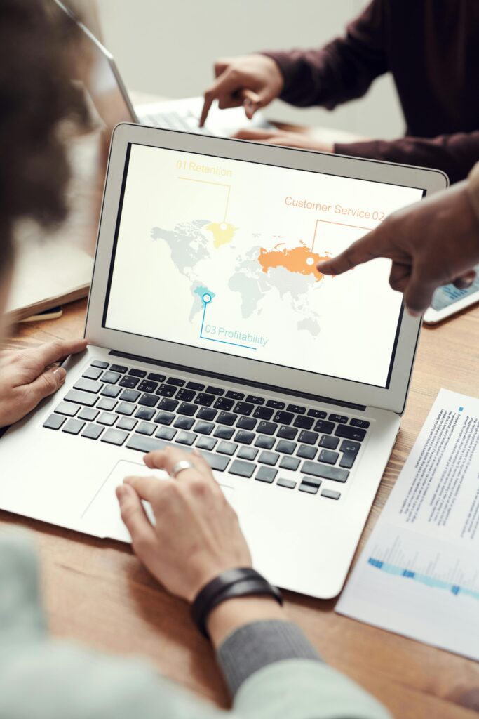 Colleagues in discussion around a laptop showing a global business presentation.